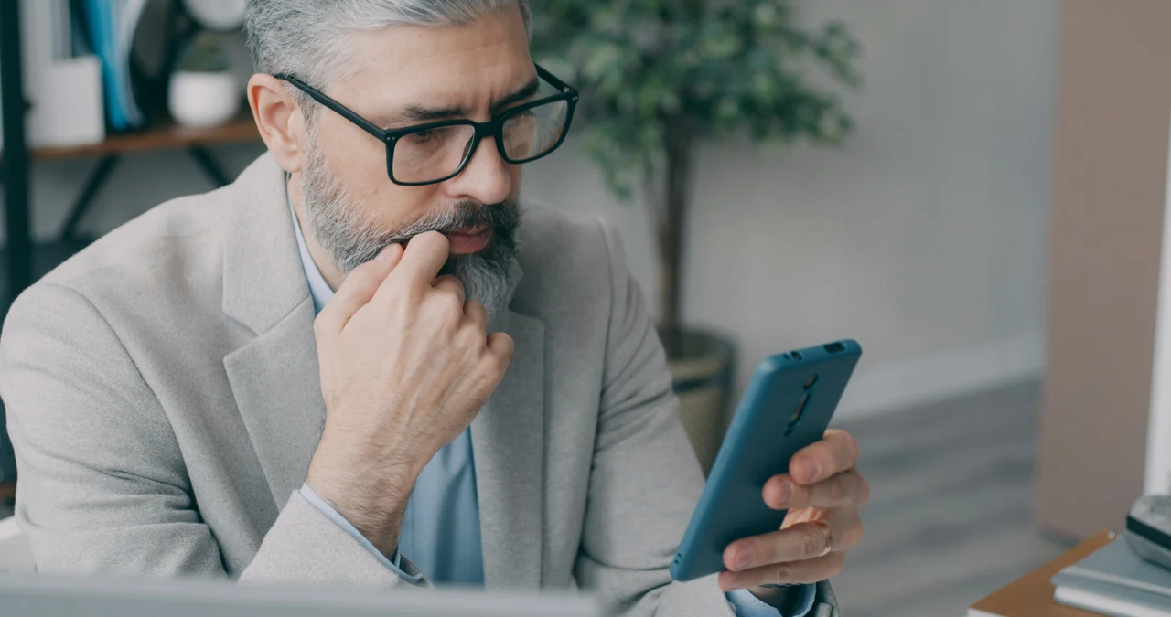 Mężczyzna telefon, sprawdzając cenę strony internetowej dla swojej firmy
